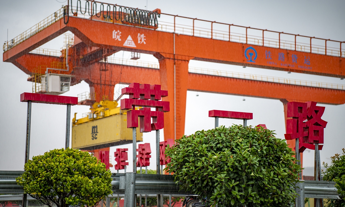 A large crane loads containers for a China-Europe freight 
train is behind a banner displaying the 